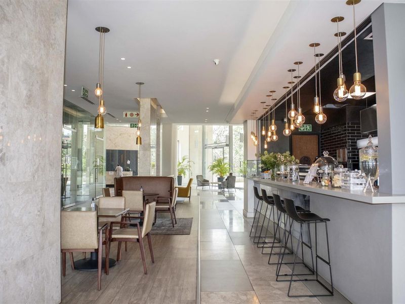Modern clubhouse area featuring a built-in bar counter, stylish pendant lighting, and large glass windows providing ample natural light.