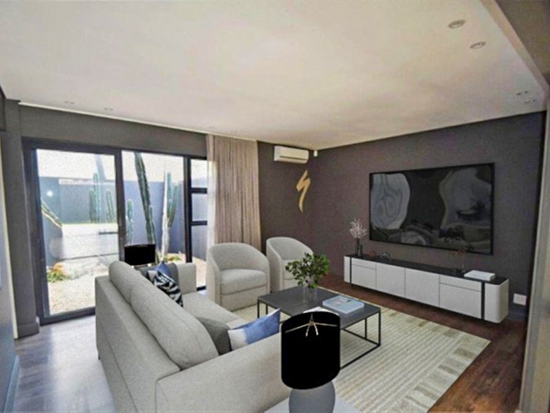 Modern living room featuring dark accent walls, laminate flooring, recessed lighting, and large sliding glass doors providing access to the outdoor area.