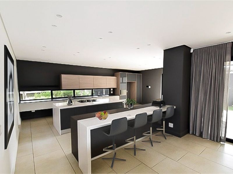 Modern kitchen featuring a large island with breakfast bar, sleek cabinetry, recessed lighting, and tiled flooring, offering a contemporary and functional cooking space.