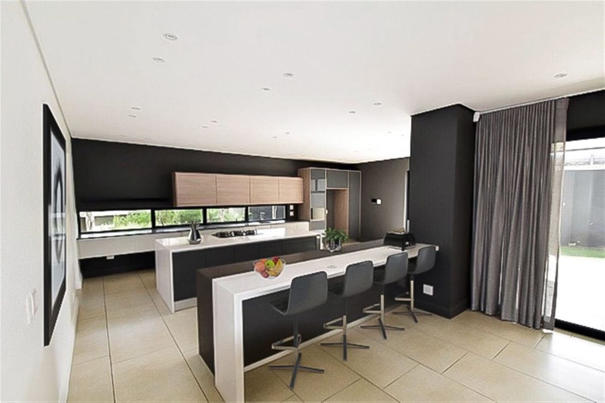 Modern kitchen featuring a large island with breakfast bar, sleek cabinetry, recessed lighting, and tiled flooring, offering a contemporary and functional cooking space.