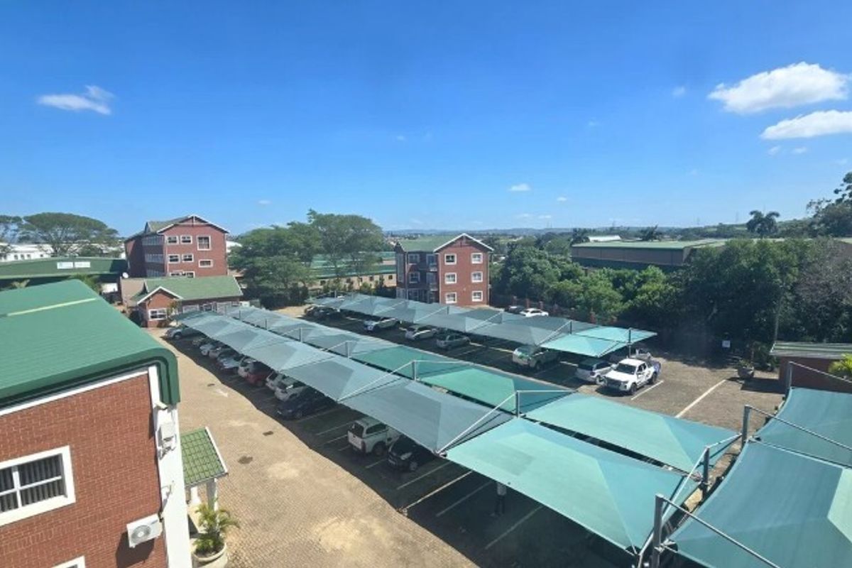 Aerial view of the office property featuring extensive paved parking areas with shade cloth carports and surrounding brick office buildings.