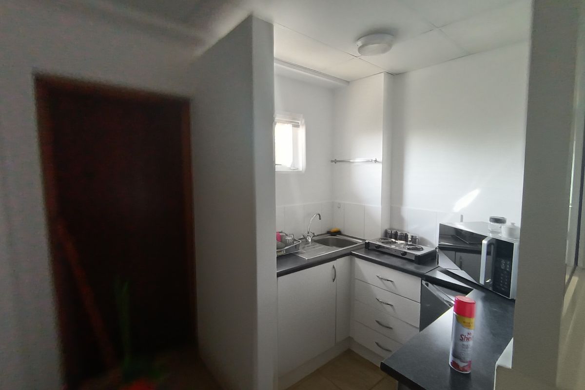 Compact office kitchenette featuring built-in cabinetry, a stainless steel sink, and a functional hob, providing essential utility for a workspace.