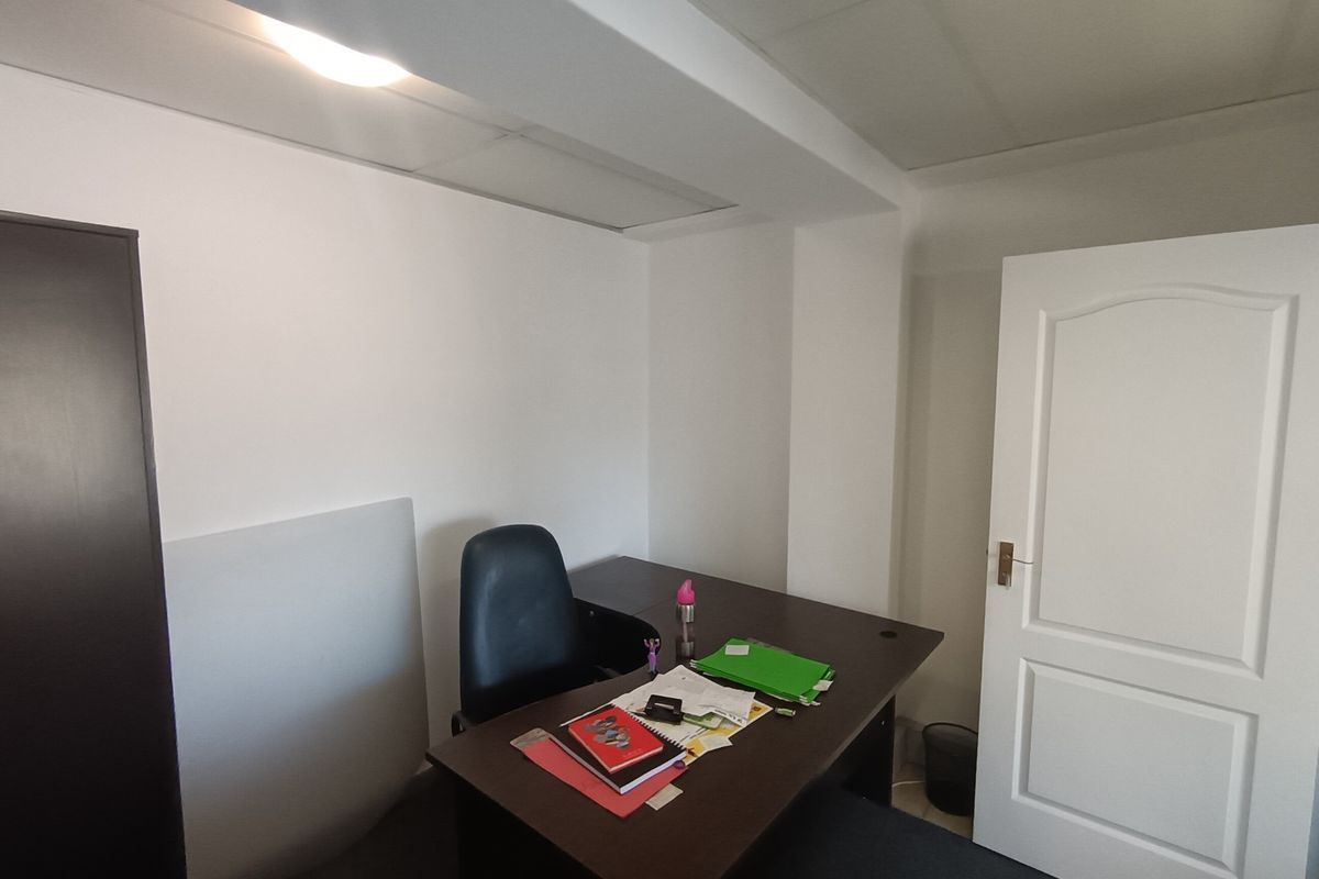A functional office space featuring a suspended ceiling with recessed lighting and a classic panel door.