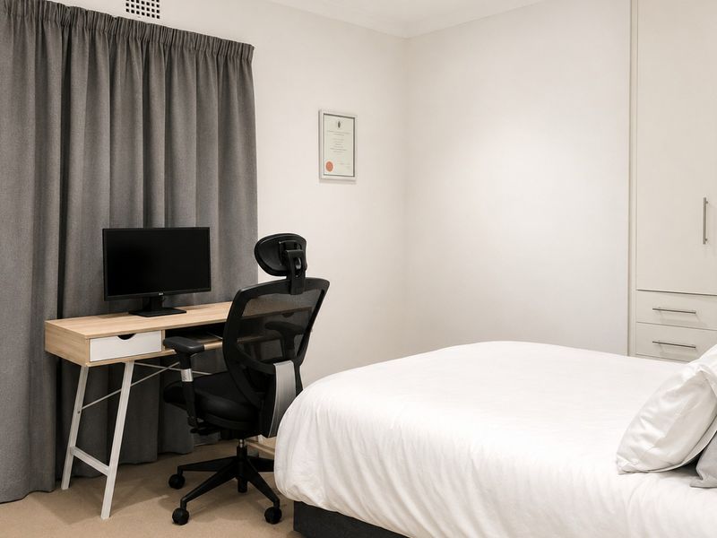A well-maintained bedroom featuring neutral walls, carpeted flooring, and a built-in wardrobe for storage.