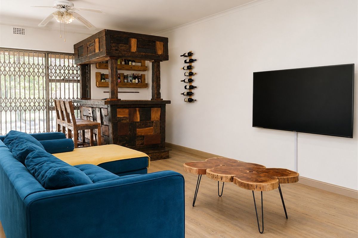 A comfortable living room featuring a custom built-in wooden bar, laminate flooring, and a ceiling fan, with direct access to an outdoor area.