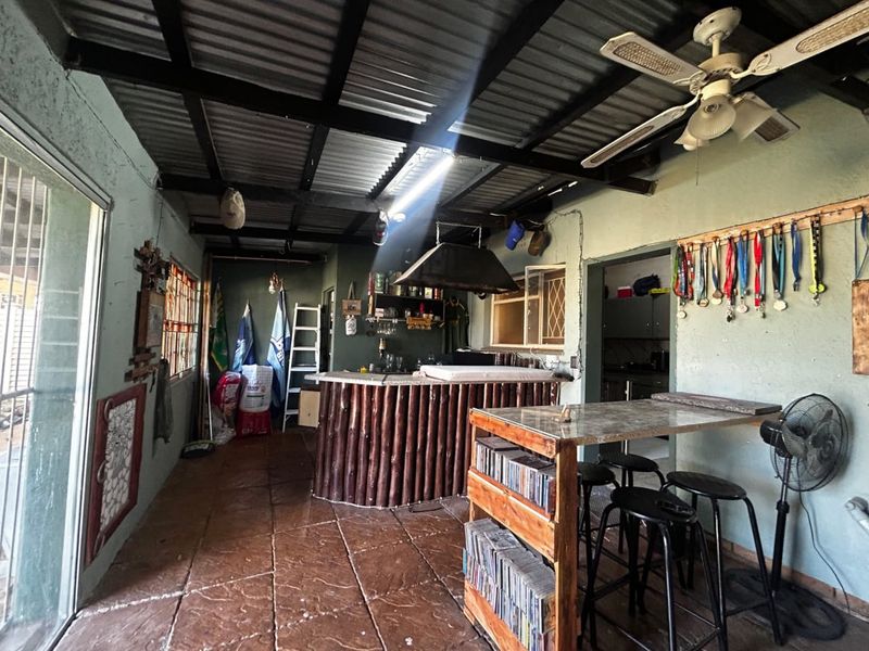 An informal indoor bar area featuring a built-in counter, extractor fan, and tiled flooring, offering a rustic entertainment space.