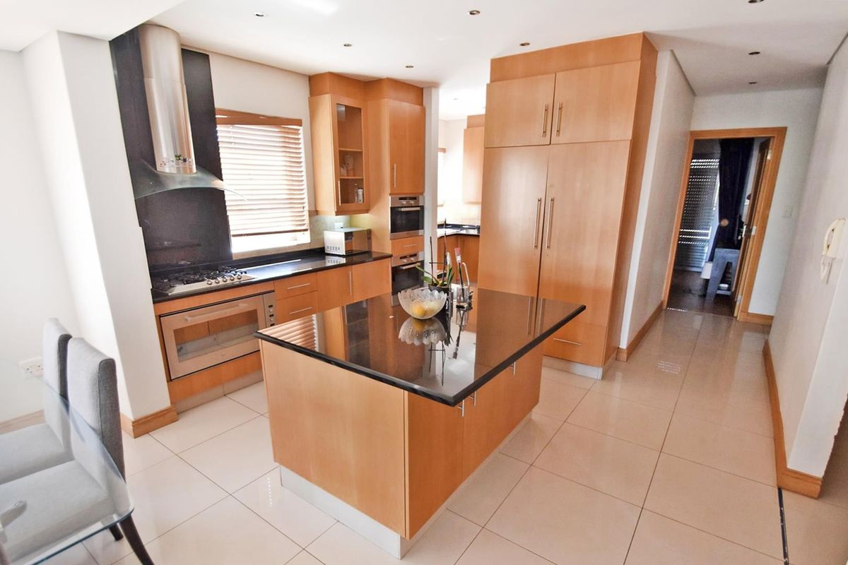 Modern kitchen featuring light wood cabinetry, granite countertops, a central island, and integrated stainless steel appliances with recessed lighting.