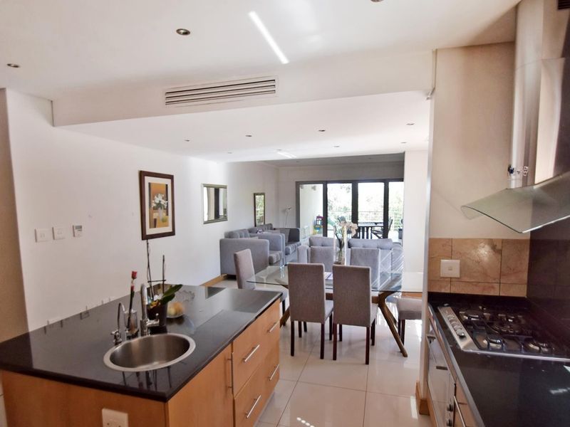 Spacious open-plan living area featuring a modern kitchen with granite countertops, gas hob, and seamless flow to the dining and lounge area.