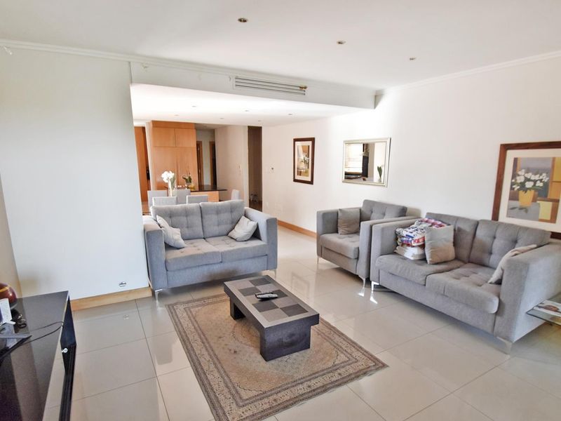 Spacious open-plan living area featuring neutral tiled flooring, recessed ceiling lighting, and integrated ducted air conditioning, flowing into the adjacent dining and kitchen space.
