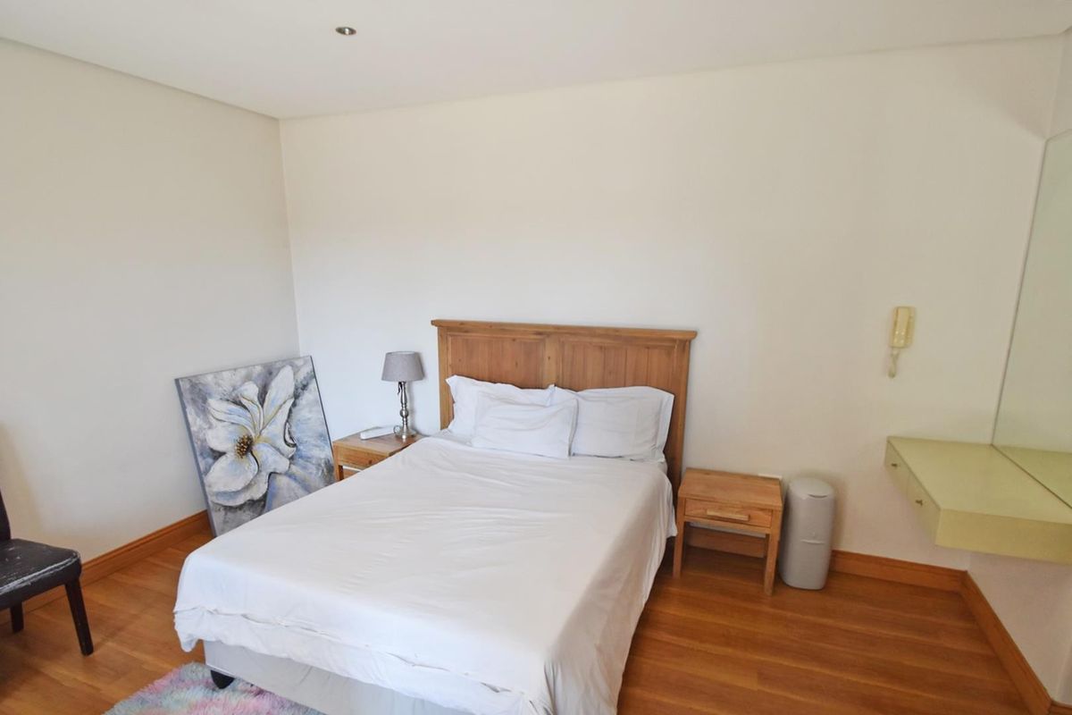 A well-lit bedroom featuring hardwood flooring, a built-in vanity shelf, and a wall-mounted intercom system.