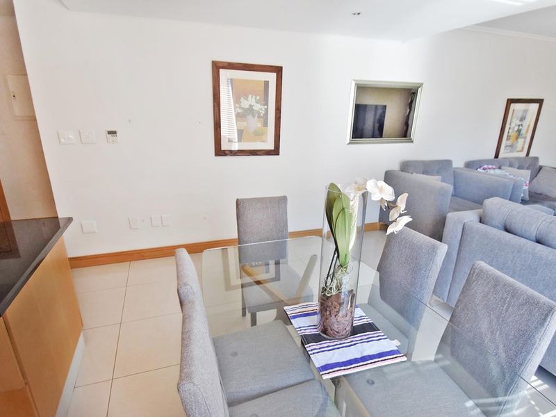 Open-plan living and dining area featuring tiled flooring, neutral walls, and a functional kitchen space with granite countertops.