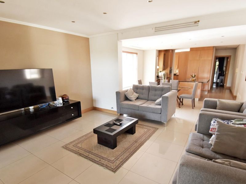 Spacious open-plan living and dining area featuring neutral tiled flooring, recessed lighting, and a seamless transition to the kitchen space.
