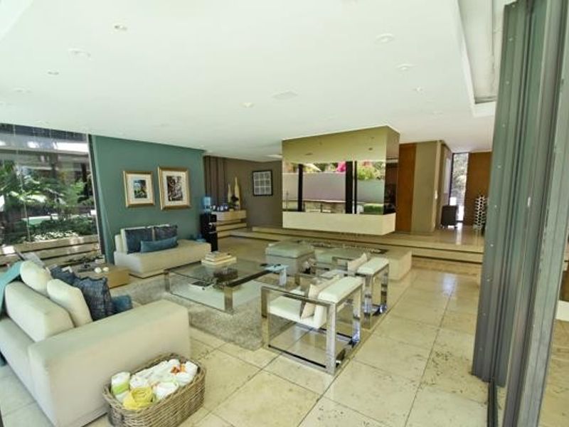 Spacious open-plan living area featuring stone tile flooring, recessed lighting, and large glass sliding doors that provide seamless access to the outdoor space.
