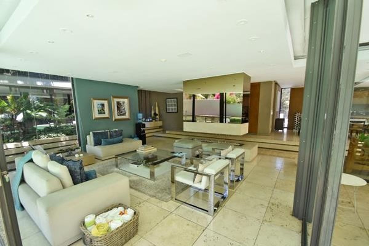 Spacious open-plan living area featuring stone tile flooring, recessed lighting, and large glass sliding doors that provide seamless access to the outdoor space.