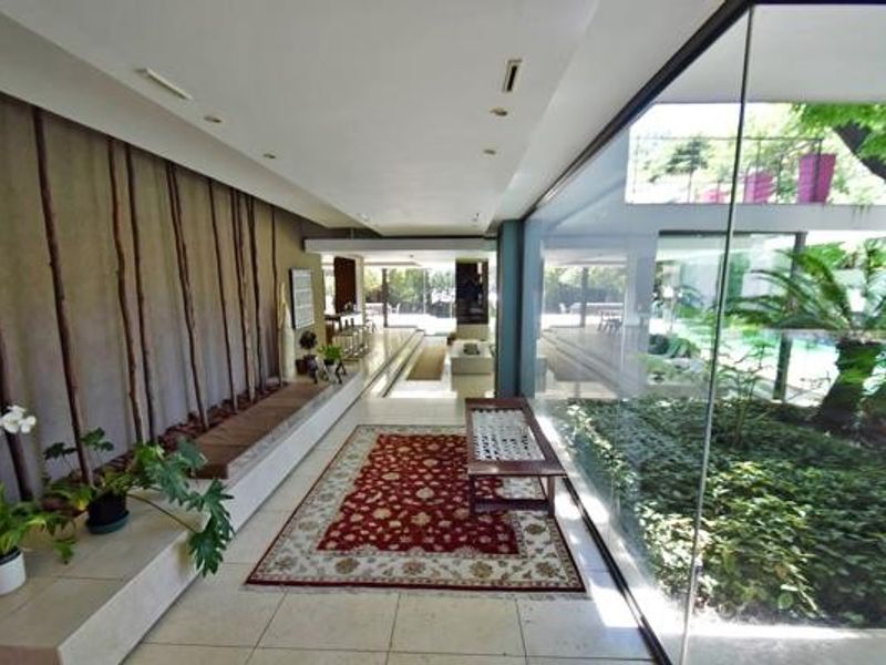 Spacious living area featuring floor-to-ceiling glass walls overlooking an internal courtyard, stone flooring, and integrated architectural lighting.