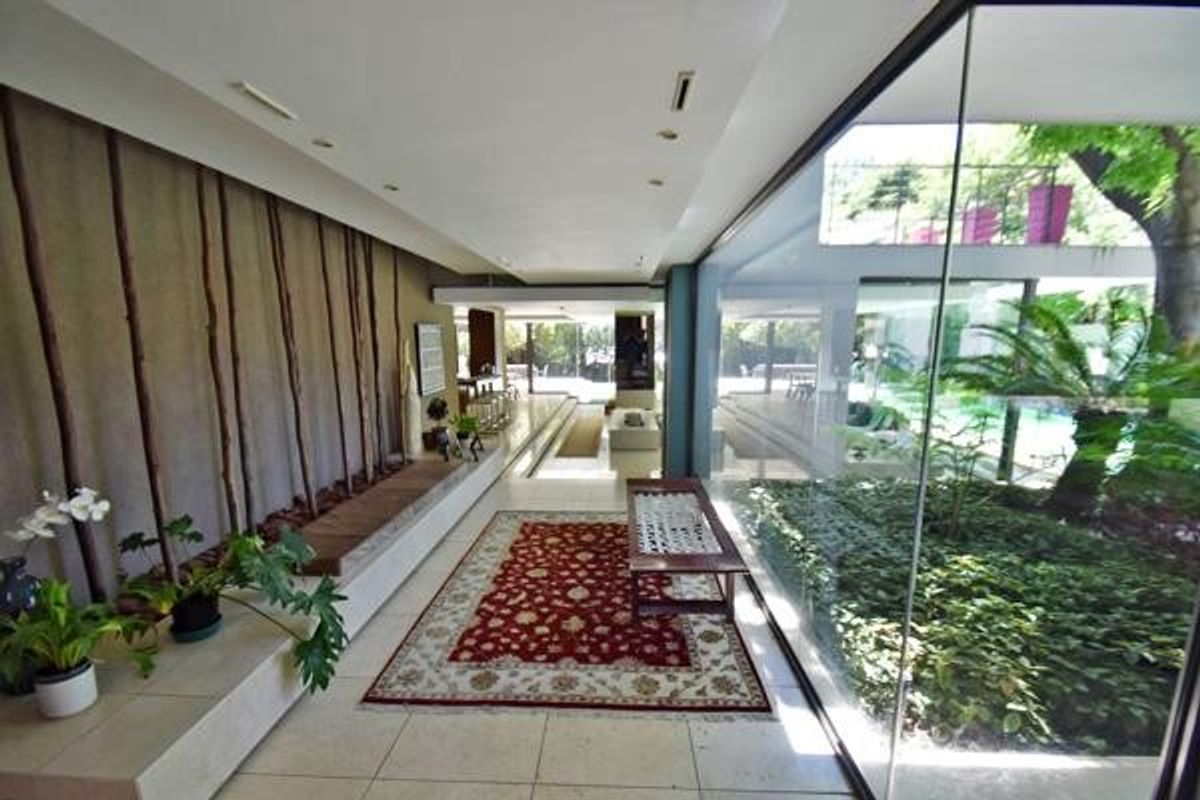 Spacious living area featuring floor-to-ceiling glass walls overlooking an internal courtyard, stone flooring, and integrated architectural lighting.