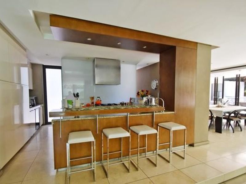 Modern open-plan kitchen featuring a granite breakfast bar, stainless steel extractor fan, and sleek built-in cabinetry, seamlessly flowing into the dining area.