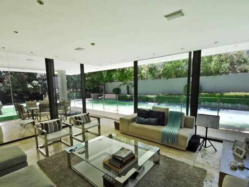 Spacious living area featuring floor-to-ceiling glass walls that provide seamless indoor-outdoor flow to the pool area and garden.