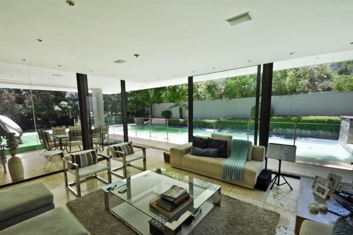 Spacious living area featuring floor-to-ceiling glass walls that provide seamless indoor-outdoor flow to the pool area and garden.