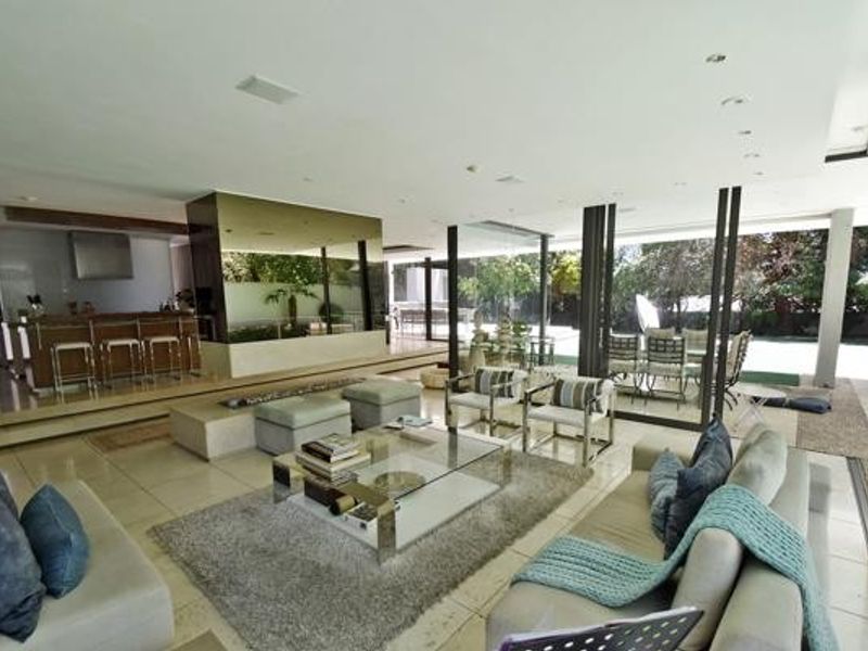 Spacious open-plan living area featuring stone flooring, recessed lighting, and seamless indoor-outdoor flow through large sliding glass doors to the patio.
