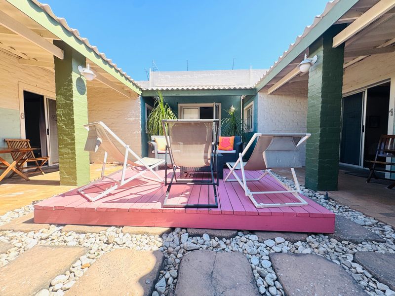 A central courtyard featuring a raised timber deck, brick pillars, and access to surrounding living areas through sliding glass doors.