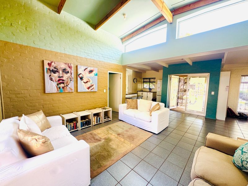 Spacious open-plan living area featuring high ceilings with exposed timber beams, clerestory windows for natural light, and direct access to the outdoor area.