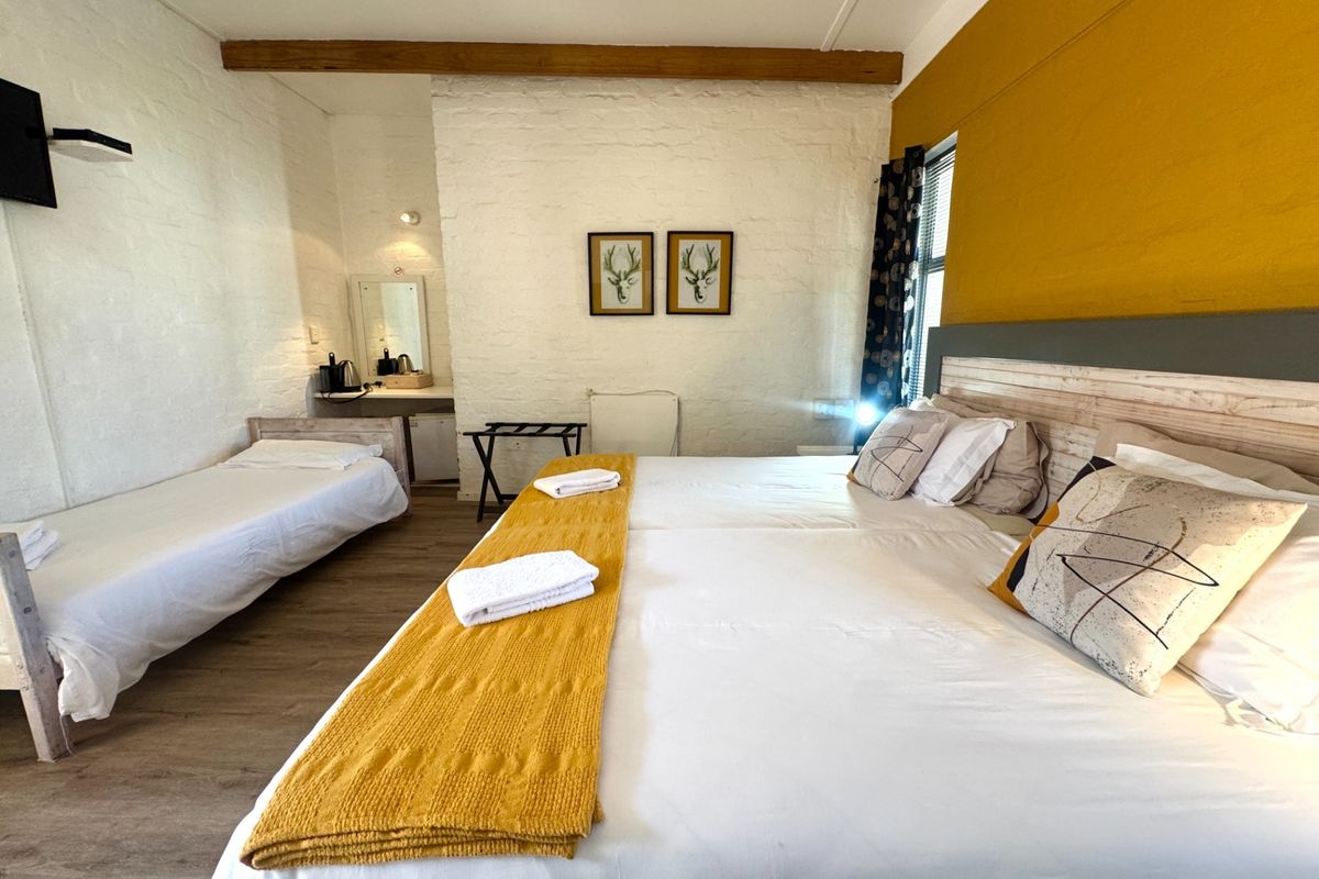 Spacious bedroom featuring exposed timber ceiling beams, painted brick walls, and a built-in vanity area.