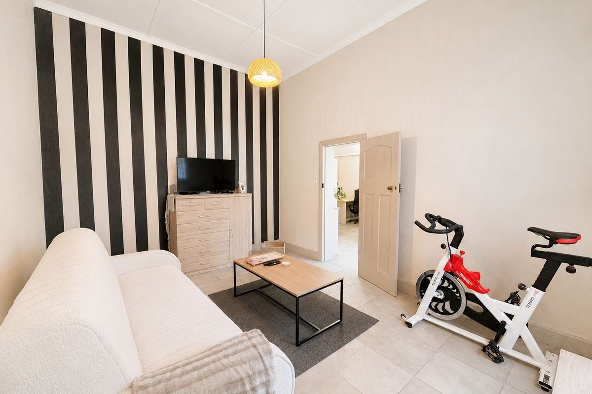 A living room featuring tiled flooring, a pendant light, and a feature wall with vertical striped wallpaper.