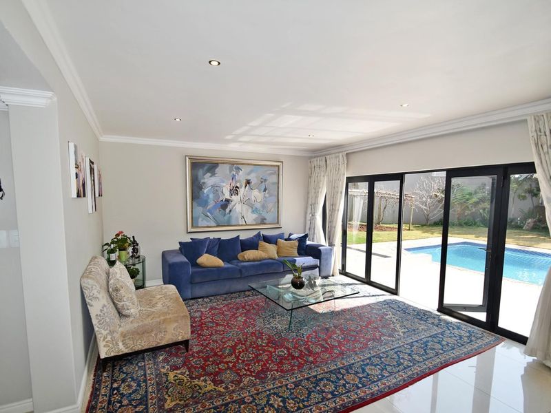 Spacious living room featuring tiled flooring, recessed lighting, and large sliding glass doors providing seamless access to the outdoor pool area.