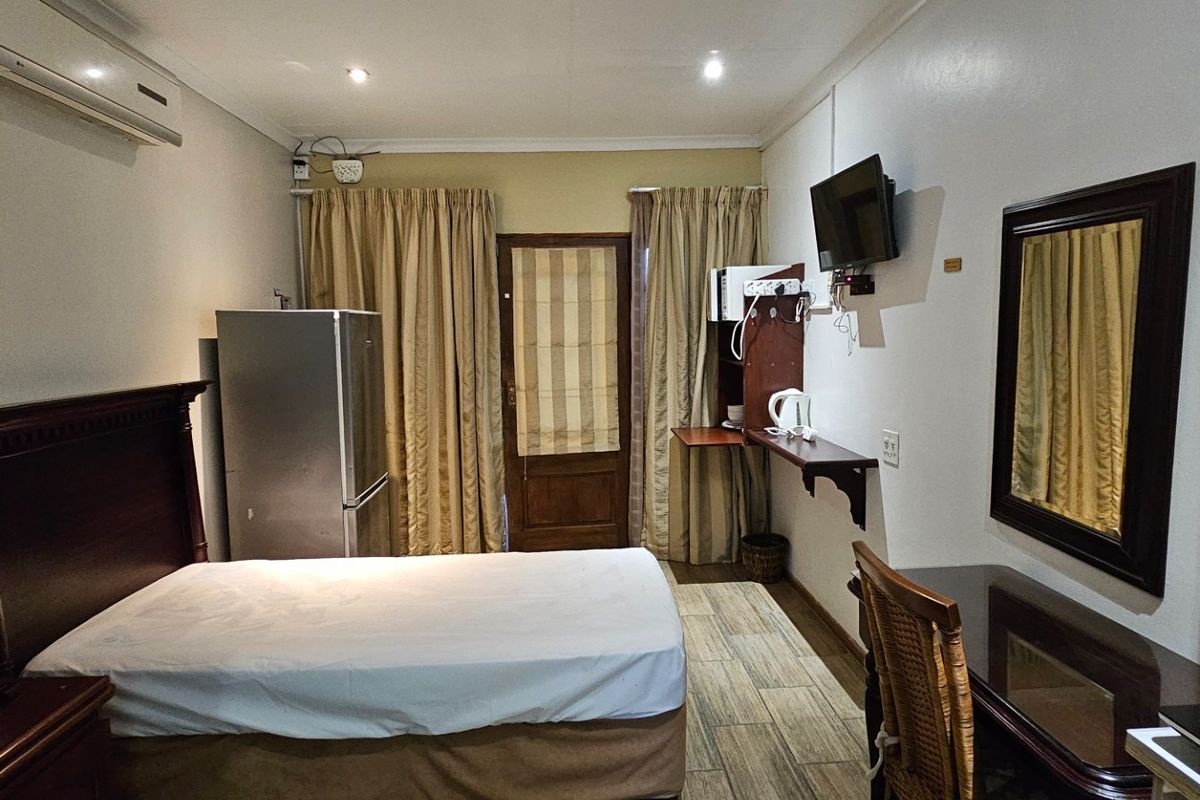 A functional bedroom featuring tiled flooring, a split-system air conditioner, and direct access to an outdoor area via a timber door.