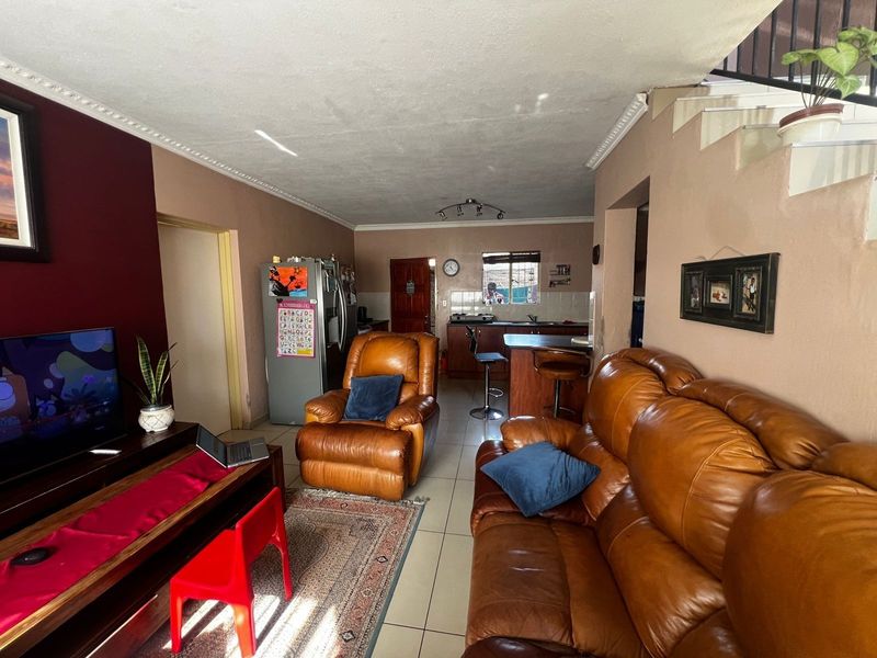 Open-plan living area featuring a combined kitchen and lounge space with tiled flooring and staircase access.