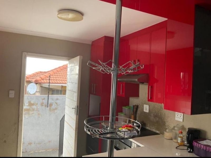 Kitchen featuring vibrant red high-gloss cabinetry, built-in hob, and extractor fan, with direct access to an outdoor area.