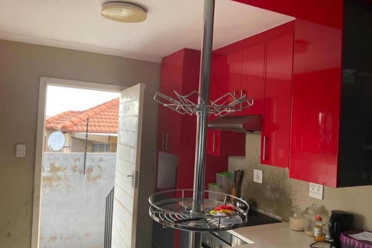 Kitchen featuring vibrant red high-gloss cabinetry, built-in hob, and extractor fan, with direct access to an outdoor area.