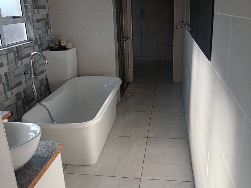 Modern bathroom featuring a freestanding bathtub, vessel sink vanity, tiled finishes, and a separate shower enclosure.