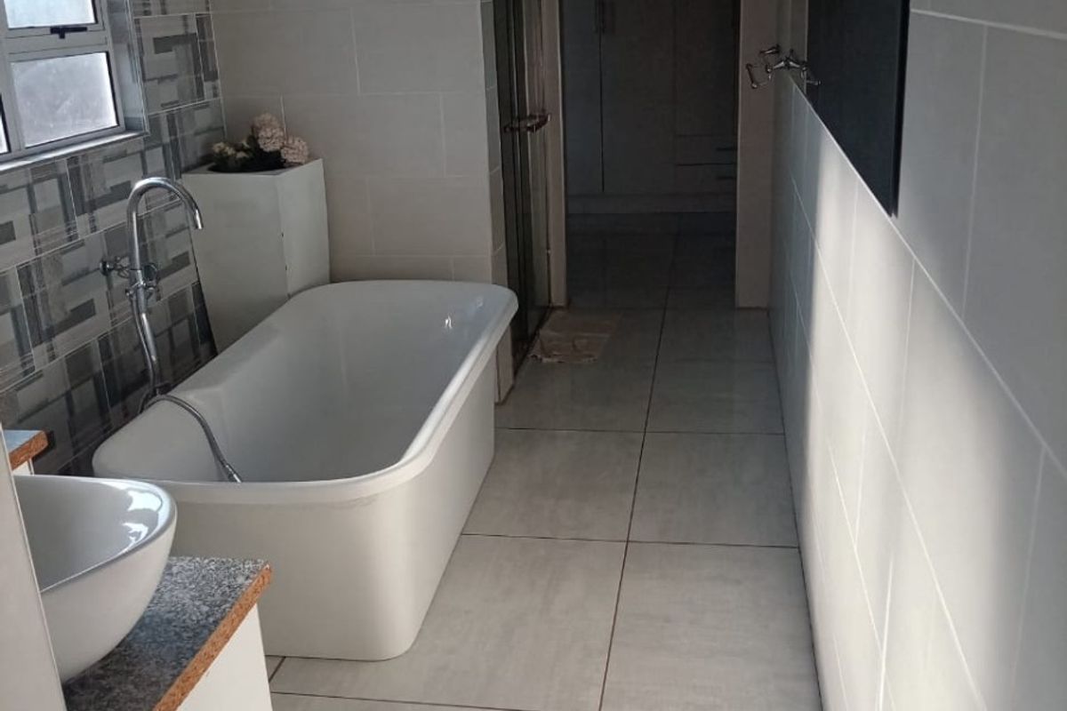 Modern bathroom featuring a freestanding bathtub, vessel sink vanity, tiled finishes, and a separate shower enclosure.