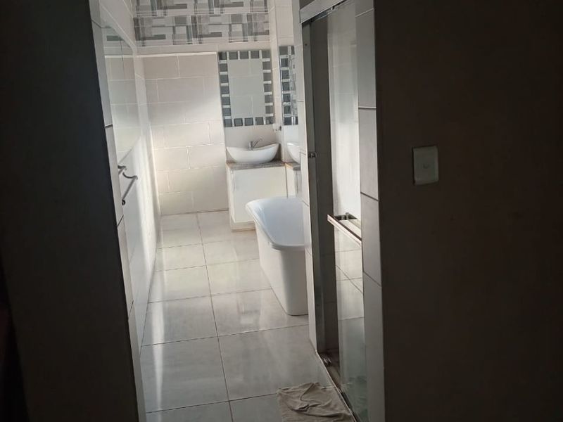 A well-lit bathroom featuring a freestanding bathtub, a modern vessel sink with vanity, and a separate shower enclosure with tiled finishes.