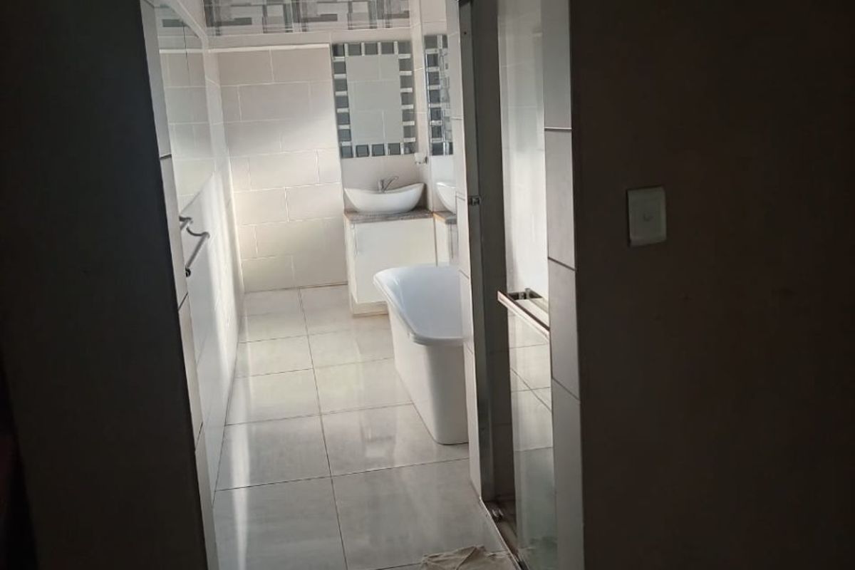 A well-lit bathroom featuring a freestanding bathtub, a modern vessel sink with vanity, and a separate shower enclosure with tiled finishes.
