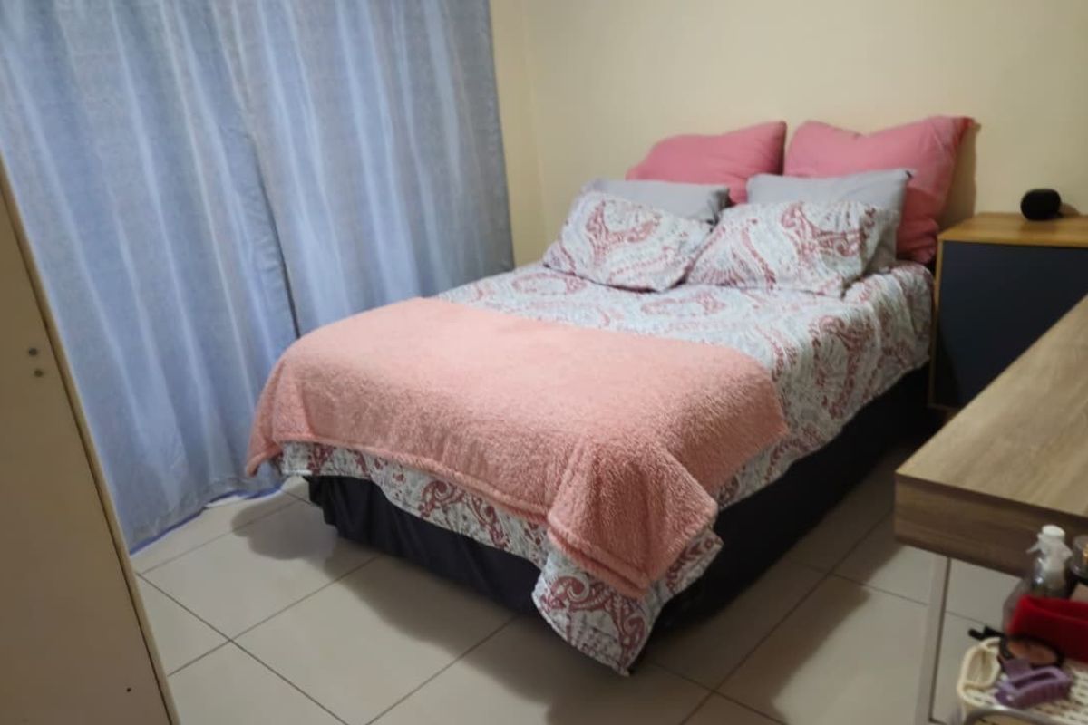A functional bedroom featuring tiled flooring and a built-in wardrobe, providing a practical and comfortable sleeping space.