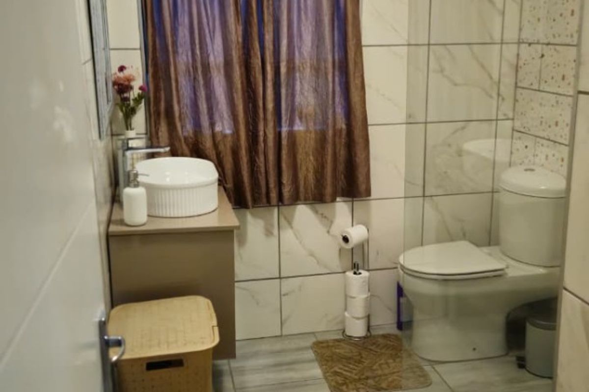 A functional bathroom featuring a vessel sink with vanity, a toilet, and a glass-enclosed shower with tiled finishes throughout.