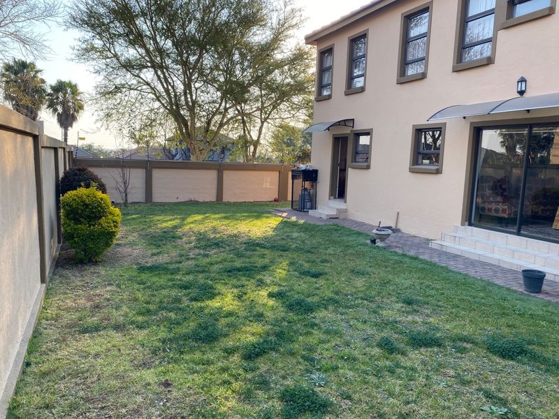 A private rear garden featuring a paved patio area, perimeter walling, and direct access to the home through sliding glass doors.