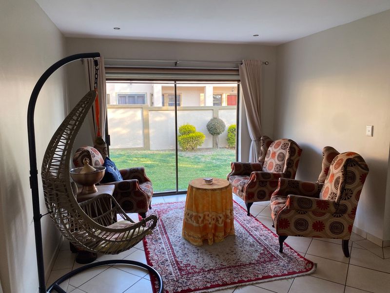 A bright living room featuring tiled flooring and a large sliding glass door that provides direct access to the rear garden.