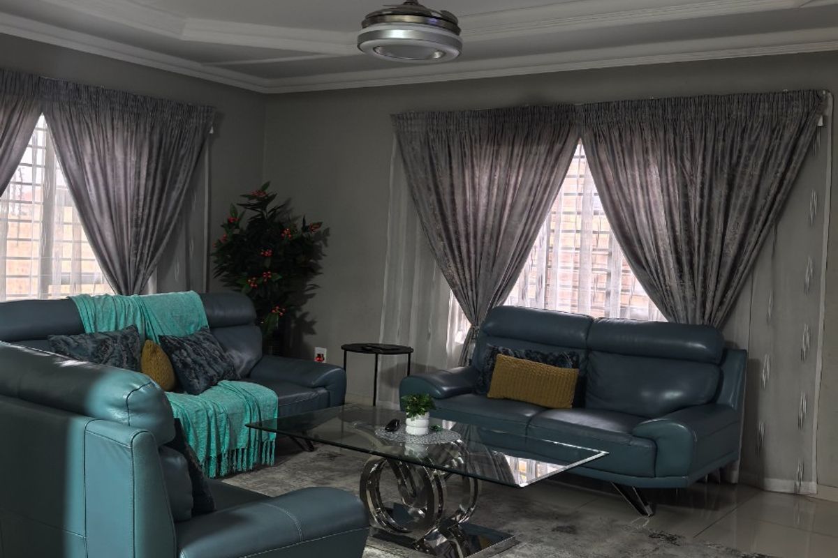 A well-maintained living room featuring tiled flooring, a central ceiling fan, and decorative recessed ceiling molding.