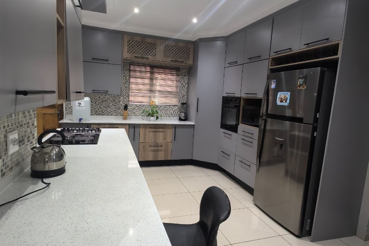 Modern kitchen featuring sleek grey cabinetry, quartz countertops, a gas hob, built-in oven, and high-quality tiled flooring with recessed lighting.