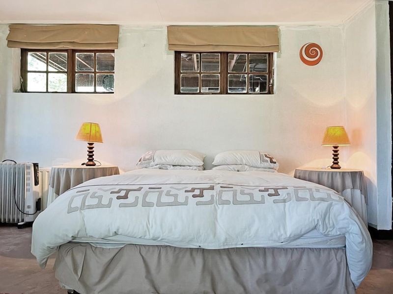 A bedroom featuring timber-framed windows and a built-in shelving unit, offering a functional space with potential for cosmetic updates.