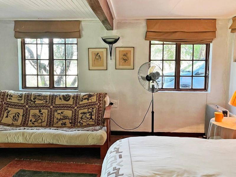 A bedroom featuring timber-framed windows, an exposed ceiling beam, and neutral wall finishes, offering a rustic aesthetic with potential for modernization.