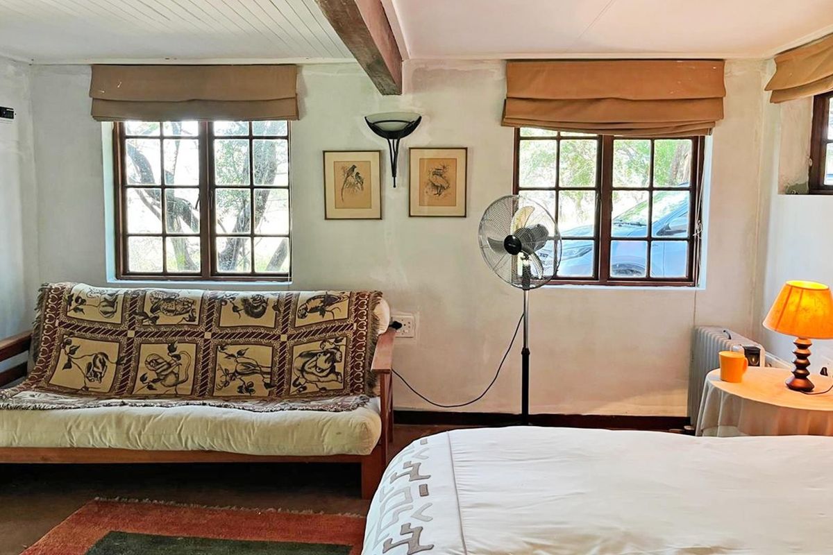 A bedroom featuring timber-framed windows, an exposed ceiling beam, and neutral wall finishes, offering a rustic aesthetic with potential for modernization.