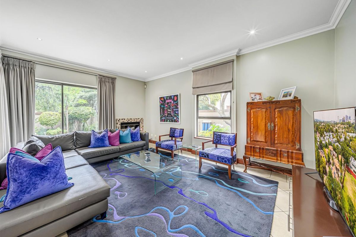 A well-maintained living room featuring tiled flooring, recessed lighting, crown molding, and a fireplace with a tiled surround, offering access to the garden.