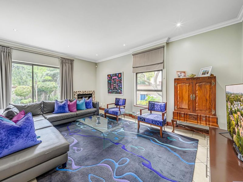 A well-maintained living room featuring tiled flooring, recessed lighting, crown molding, and a fireplace with a tiled surround, offering access to the garden.