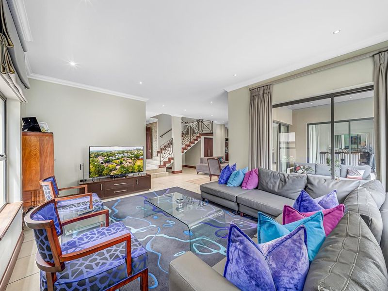 Spacious open-plan living area featuring recessed downlights, elegant cove cornicing, and large sliding glass doors that provide seamless access to the outdoor patio.