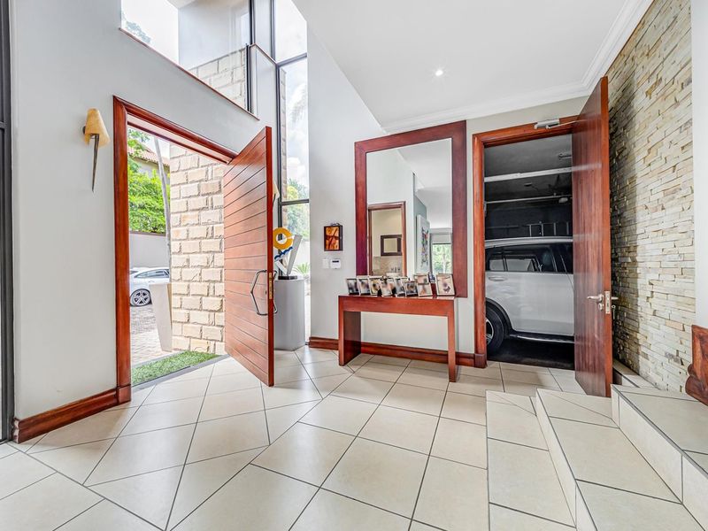 Spacious double-volume entrance hall featuring tiled flooring, a striking stone feature wall, and large windows that provide abundant natural light.